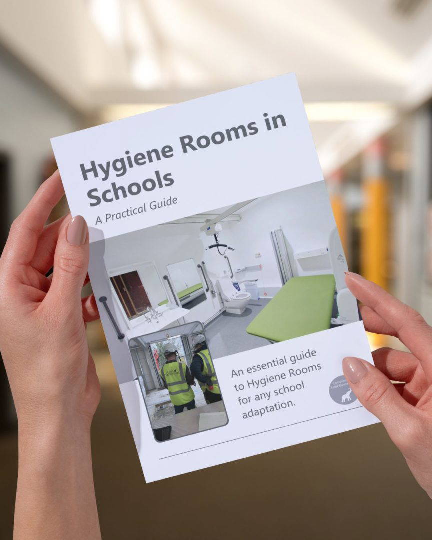 A person holding a document with a picture of an accessible bathroom and the words 'Bathroom Adaptations and DFG Funding'